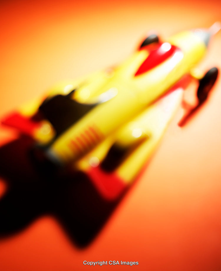 Blurred Close-Up of a Yellow and Red Plastic Rocket Toy
