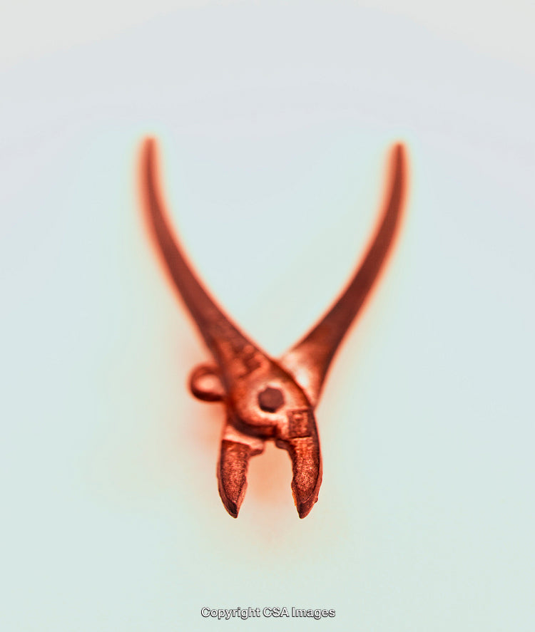 Close-Up of a Small Copper-Colored Toy Tool on Light Background