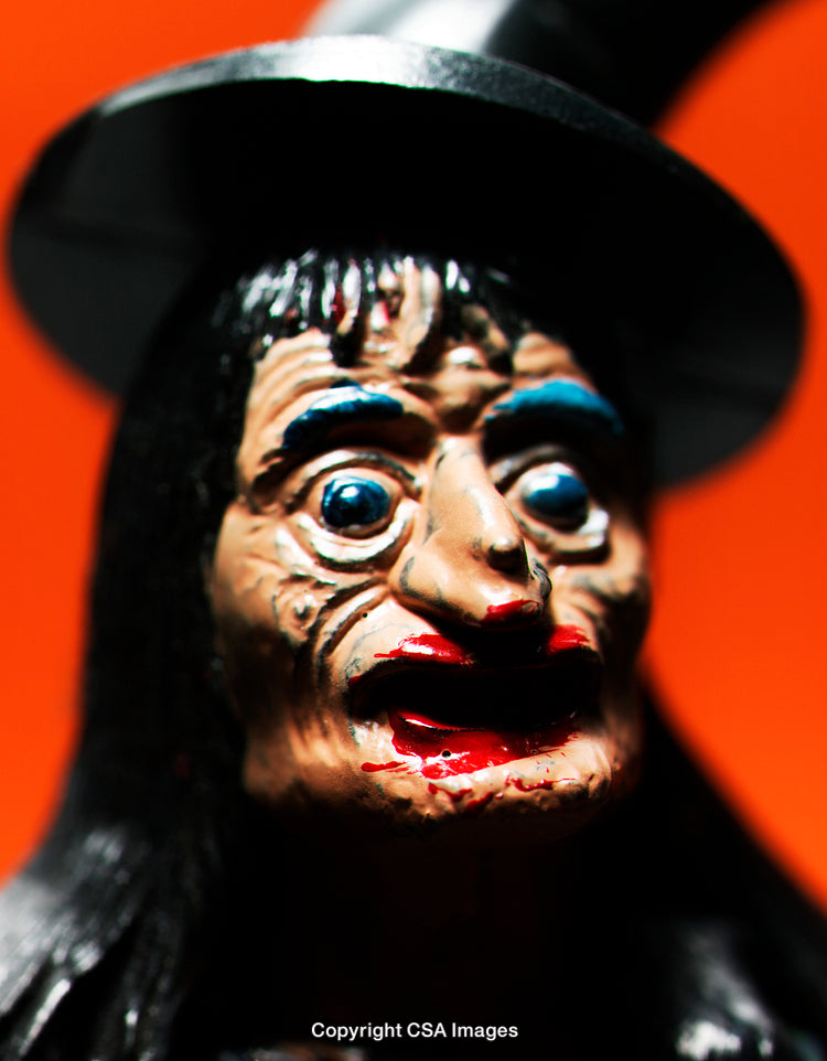 Close-Up of a Detailed Figurine of a Witch with Orange Background