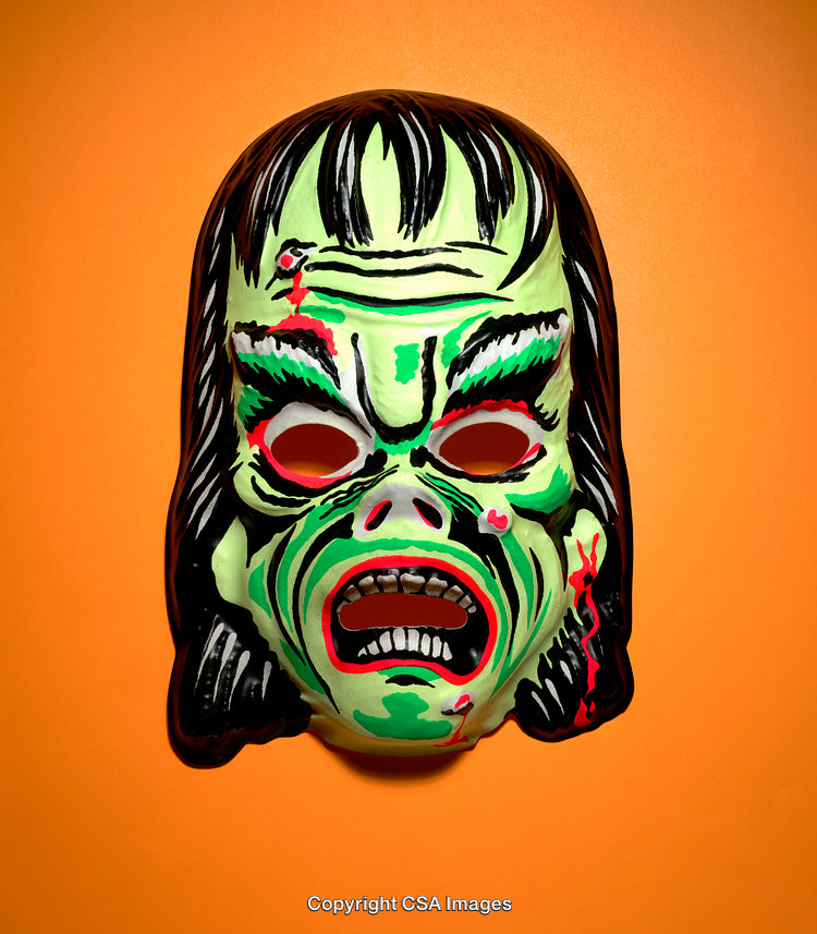 Green Monster Halloween Mask Against Orange Background