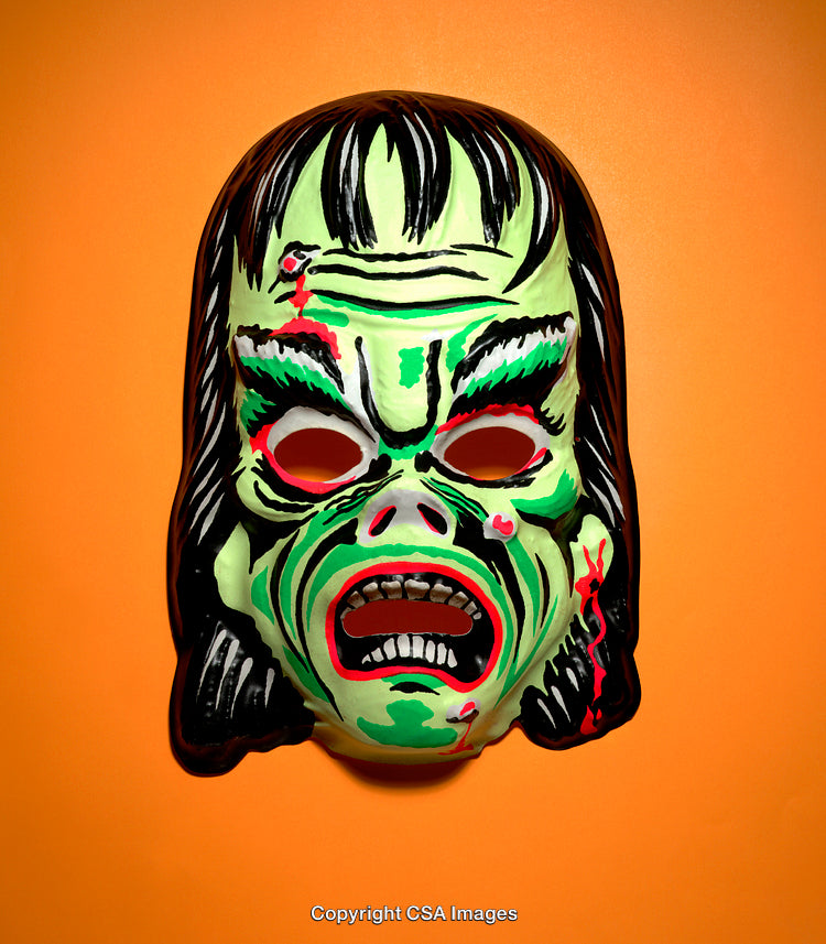 Green Monster Halloween Mask Against Orange Background