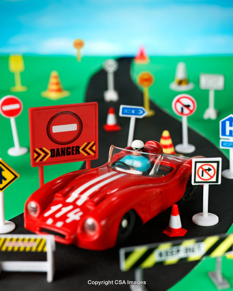Red Toy Car Among Road Signs on Miniature Road Setup