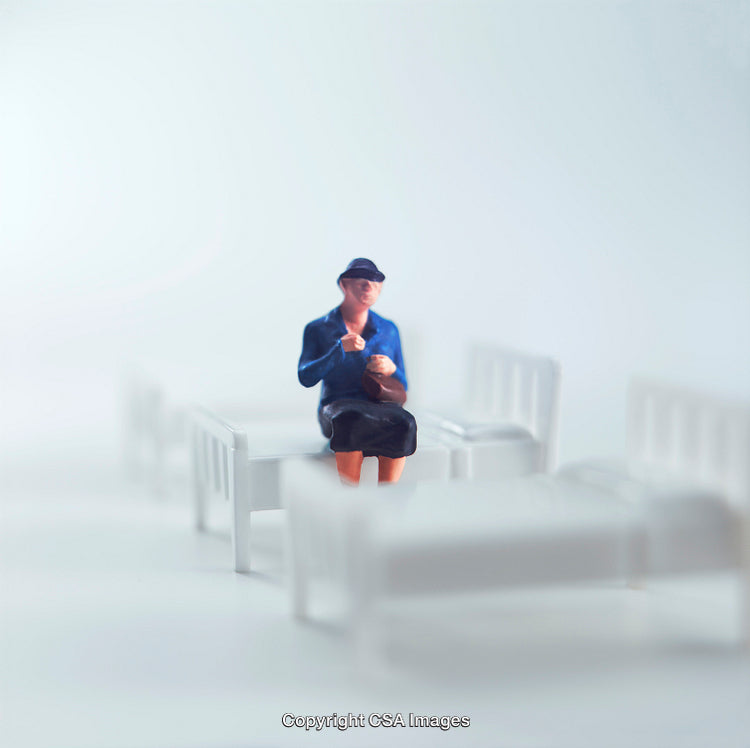 Miniature Figure Sitting on a Bed in a White Background Setting
