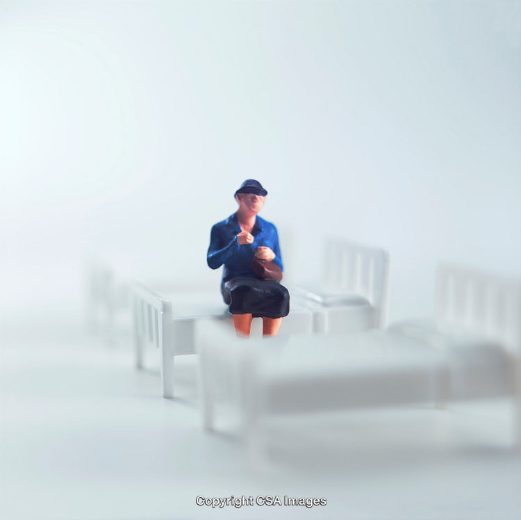 Miniature Figure Sitting on a Bed in a White Background Setting