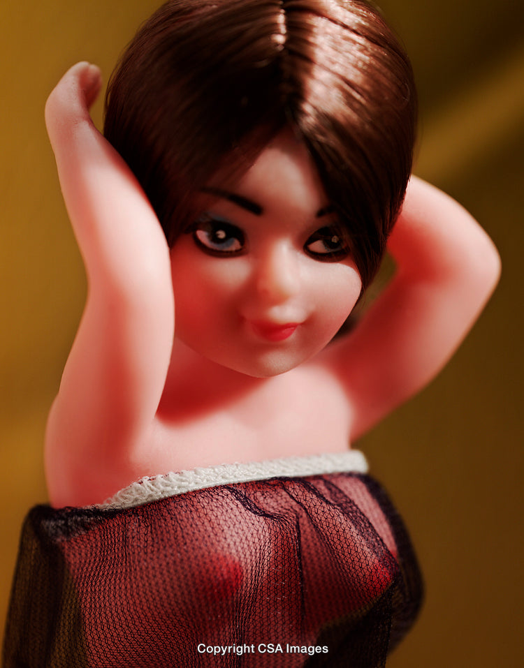 Close-Up Shot of a Plastic Doll Figure Against a Yellow Background