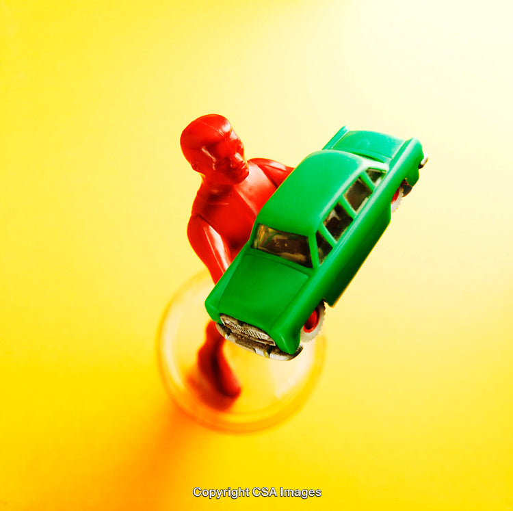 Red Toy Figure Holding Green Car on Vibrant Yellow Background