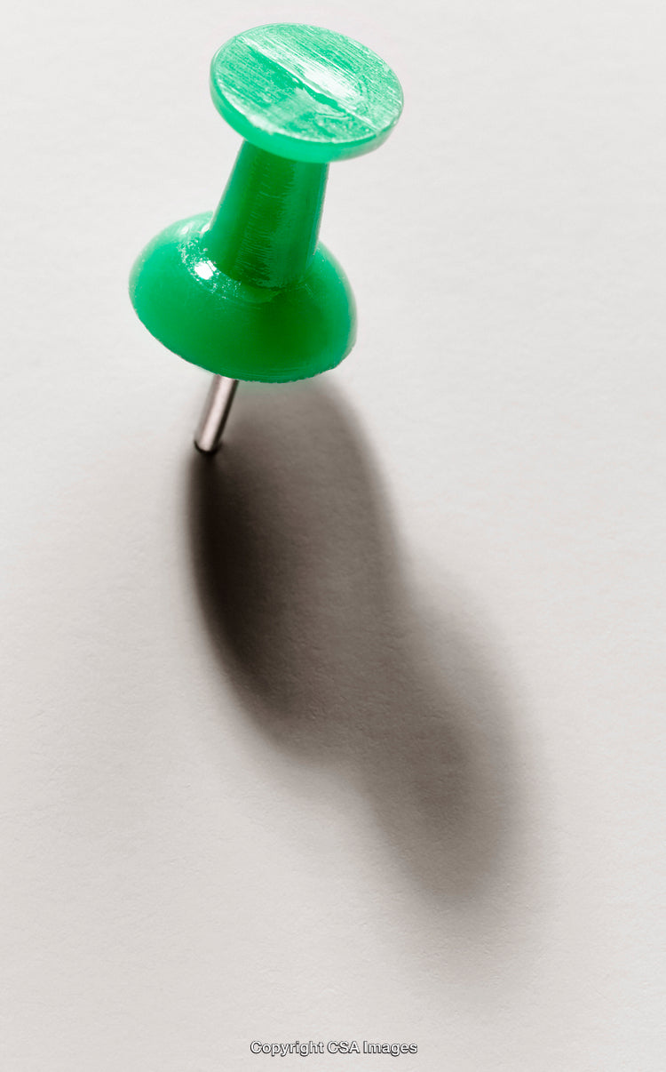 Green Thumbtack with Shadow on a Bright Surface Close-Up