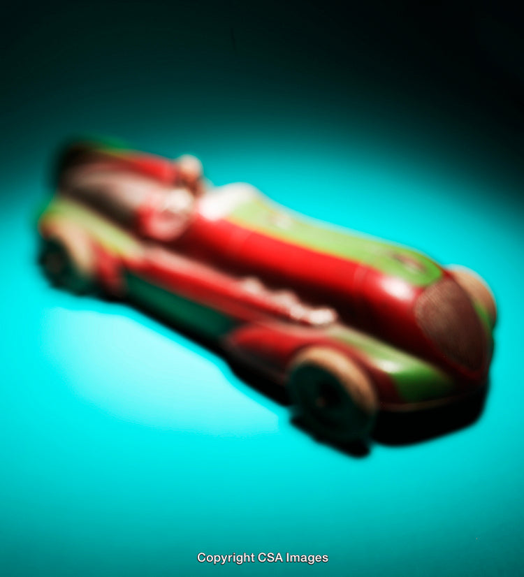 Vintage Toy Car on Vibrant Turquoise Background with Artistic Motion Blur Effect