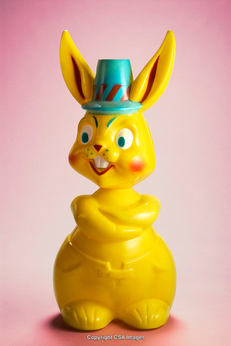 Bright Yellow Plastic Bunny Figure Against Pink Background