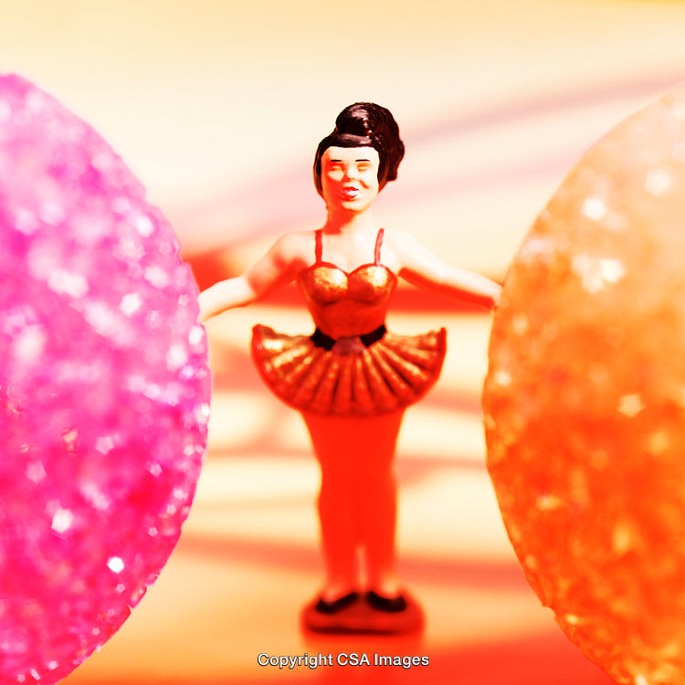 Close-Up of a Colorful Plastic Ballerina Figurine Surrounded by Vibrant Bright Spheres