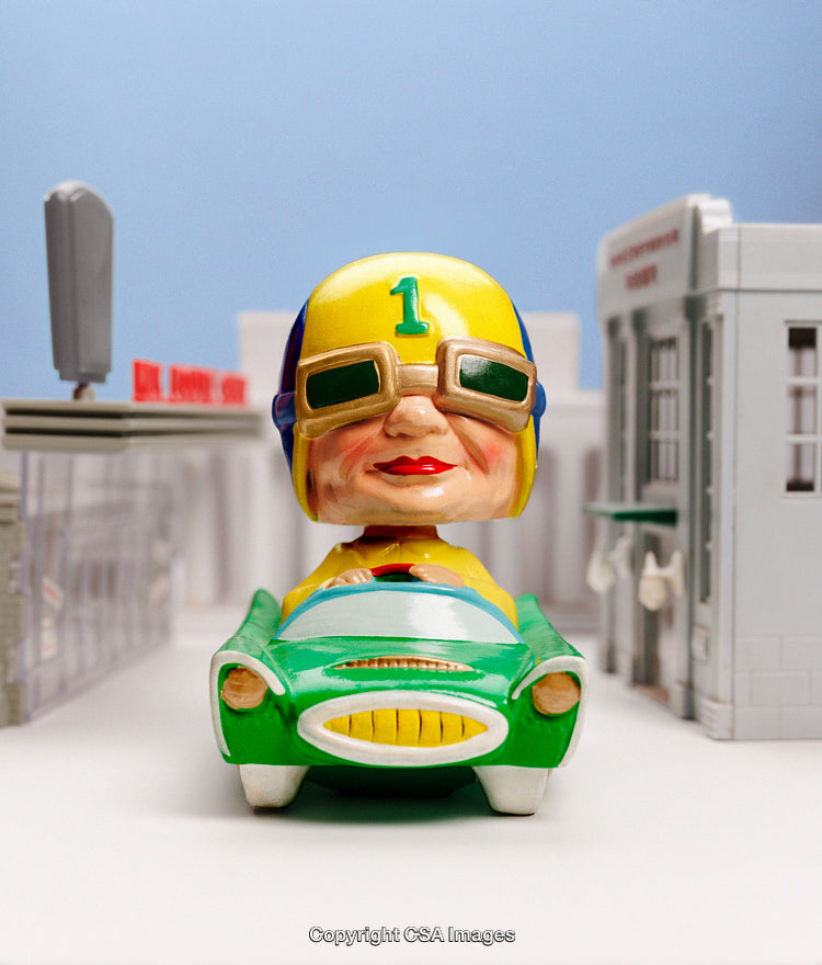 Colorful Toy Figure in a Miniature Car in a Cityscape Setting