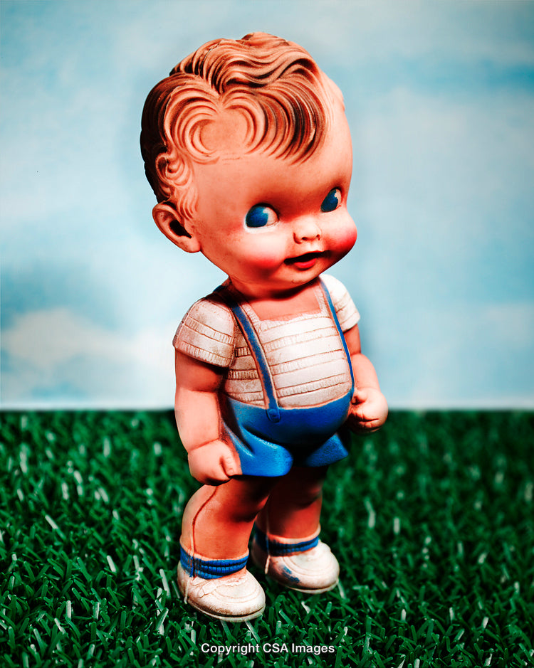 Vintage Toy Figure of a Smiling Child on a Grassy Background
