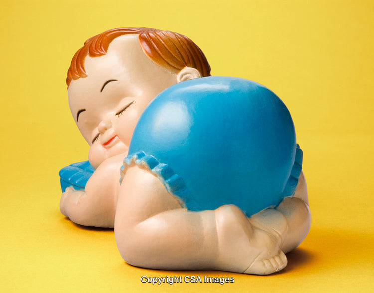 Ceramic Baby Figurine Resting on Yellow Background with Blue Diaper