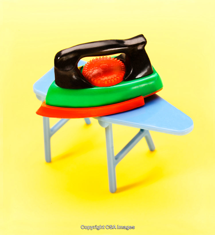 Colorful Plastic Toy Iron on Miniature Ironing Board with Yellow Background