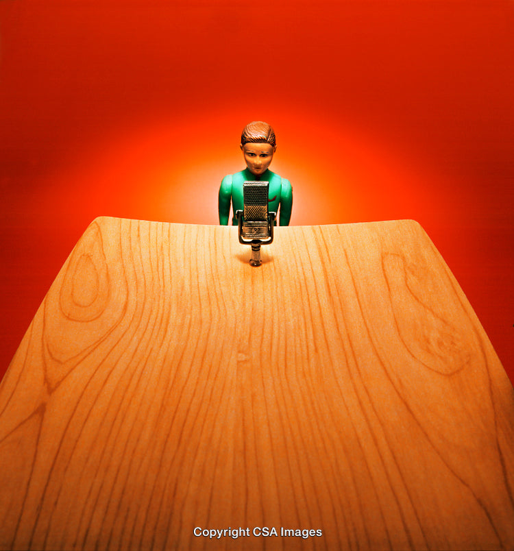 Toy Figure Speaking at a Microphone Against a Red Background