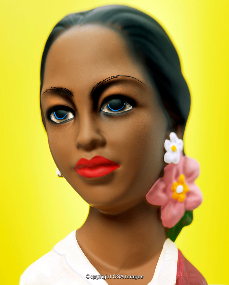Colorful Figurine of a Woman with Flower Adornments on Yellow Background