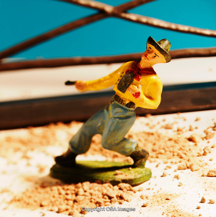 Plastic Toy Cowboy Figure in Action on Sandy Terrain