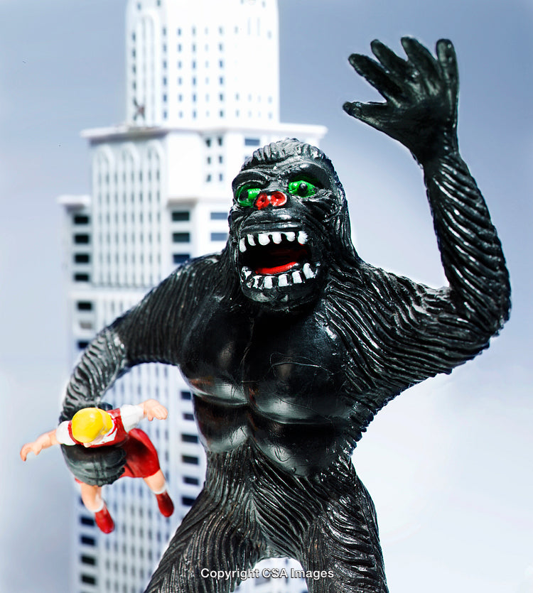 Plastic Gorilla Figure Holding a Doll with City Backdrop