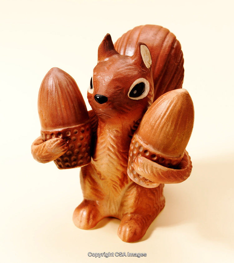 Brown Squirrel Figurine Holding Two Acorns on a Light Background