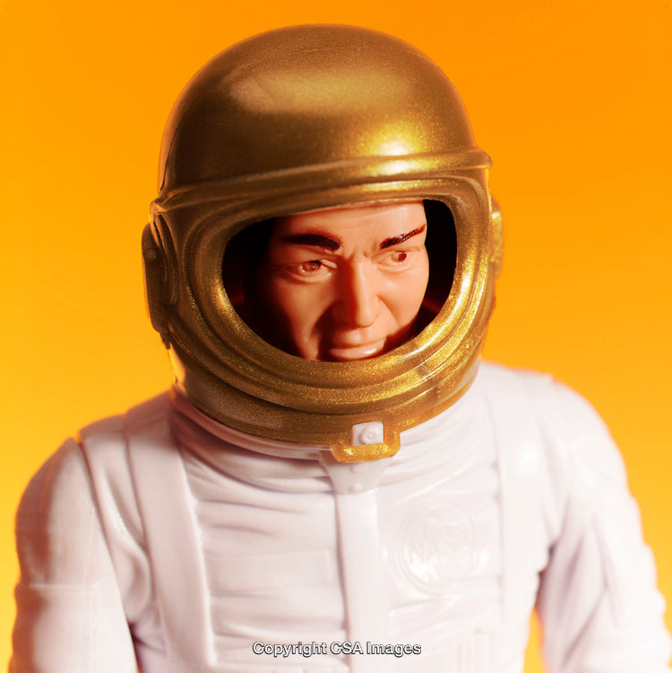 Close-Up of Toy Astronaut Figure with Gold Helmet on Orange Background