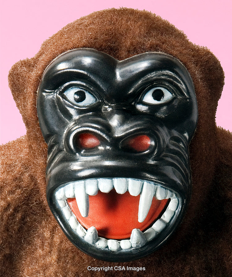Close-Up of Plastic Gorilla Toy With Fierce Expression Against Pink Background