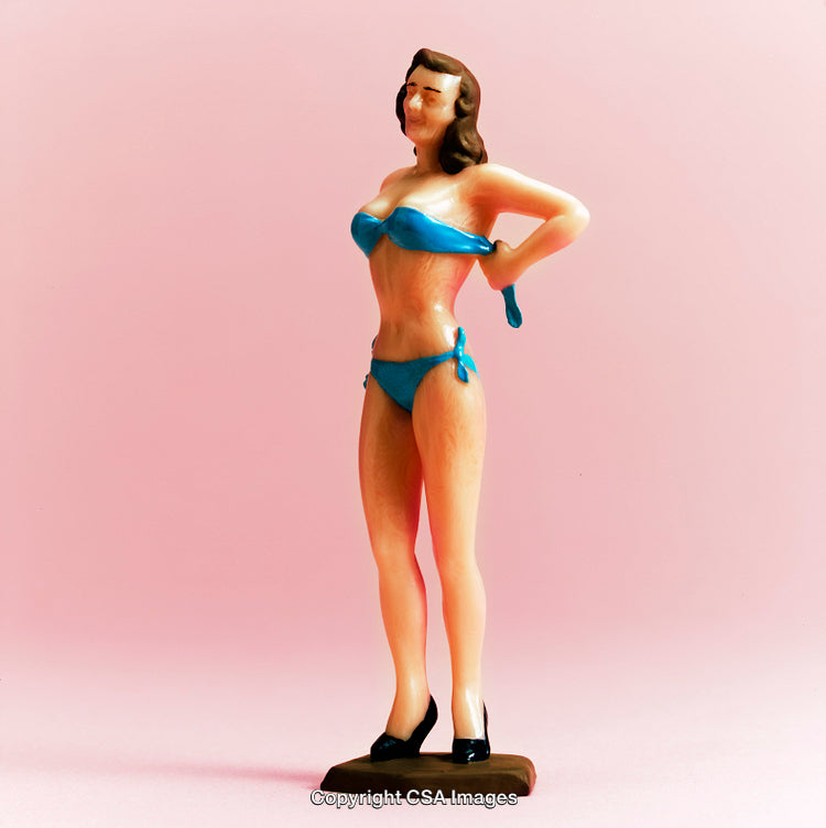 Retro Plastic Figurine of Woman in Blue Swimsuit Against Pink Background