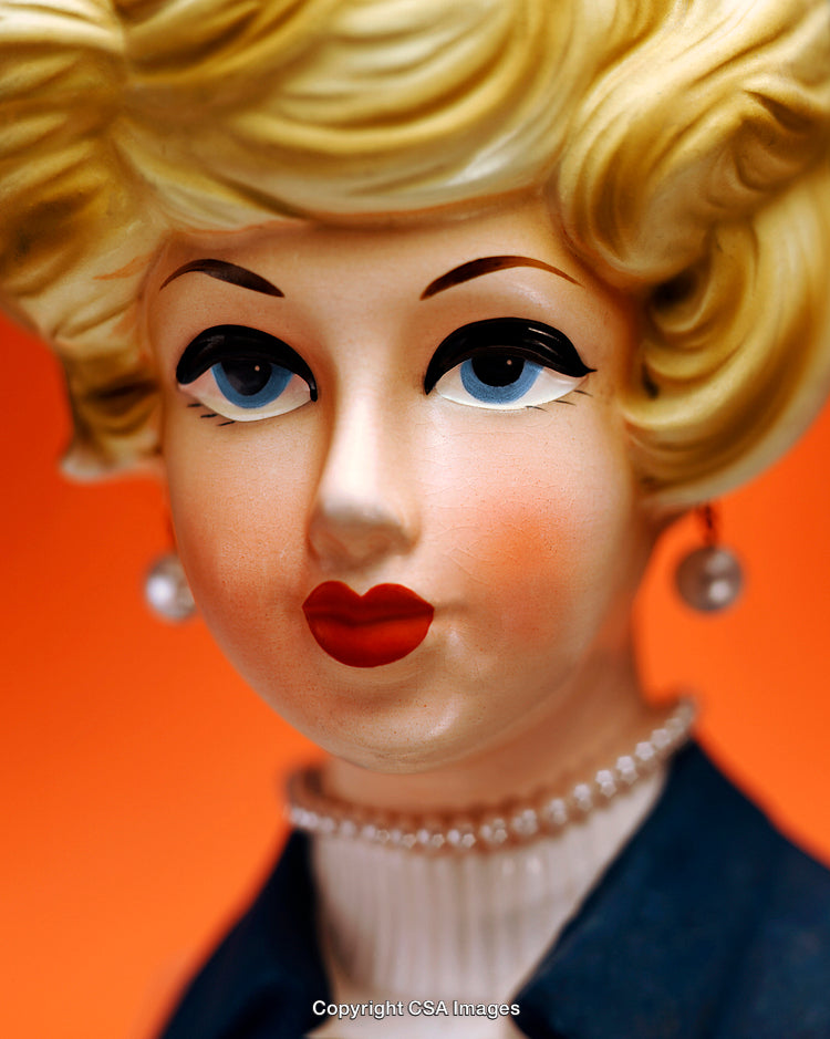 Vintage Doll Figurine with Pearl Earrings Displayed on Orange Background