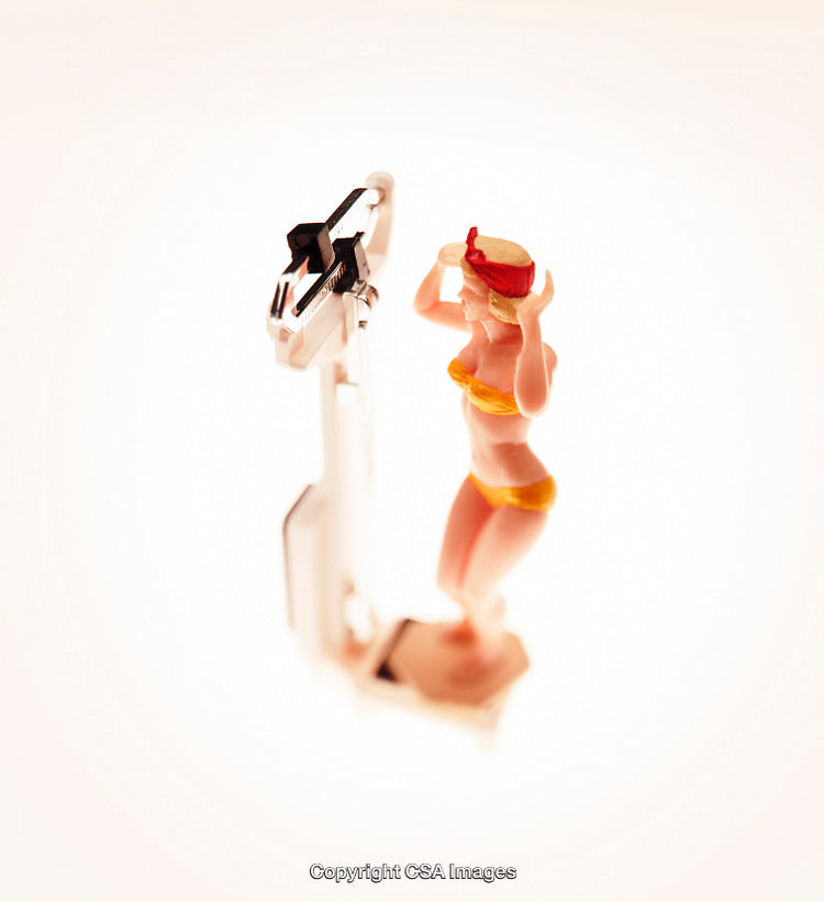 Plastic Toy Figure of Woman Standing on Scale in Bright Light