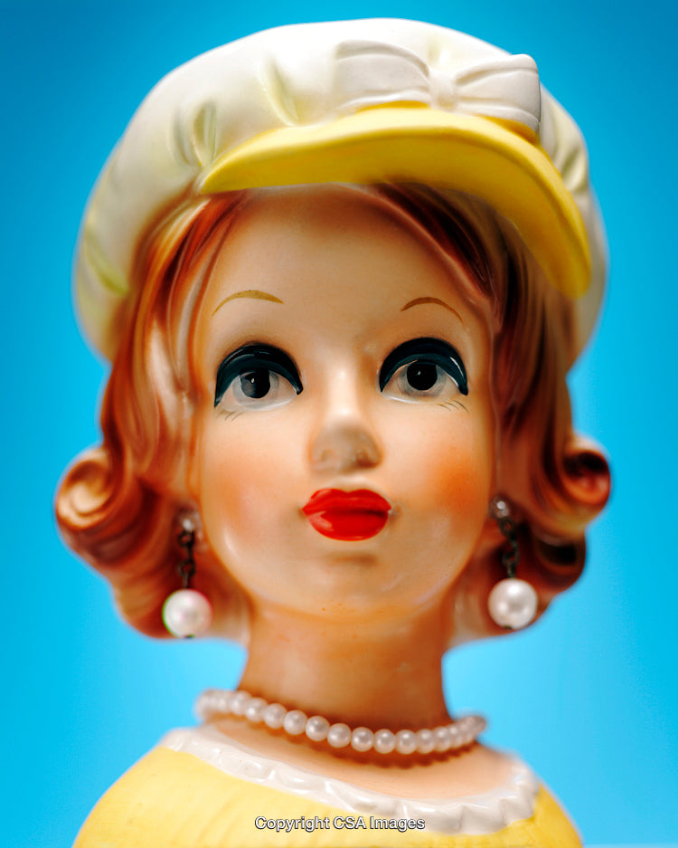 Vintage Porcelain Doll Figurine With Pearl Jewelry and Yellow Hat on Blue