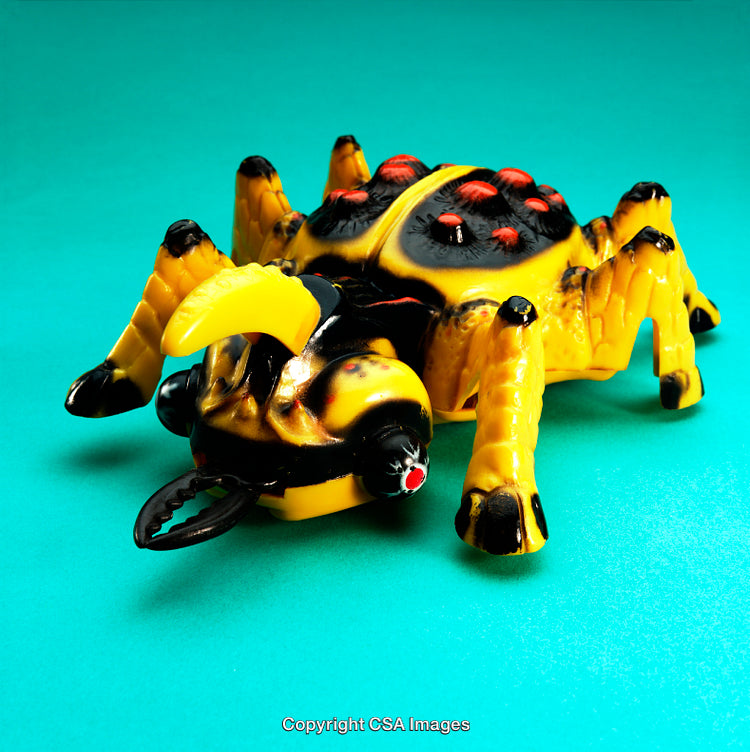 Yellow and Black Spider-Inspired Toy on Teal Background