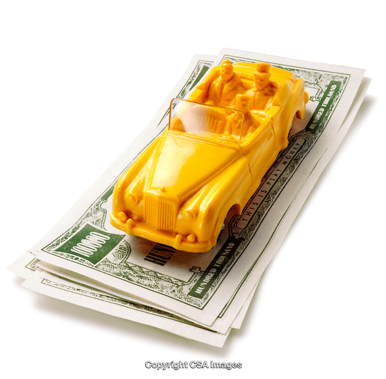 Yellow Toy Car on Stack of Play Money Representing Wealth and Luxury