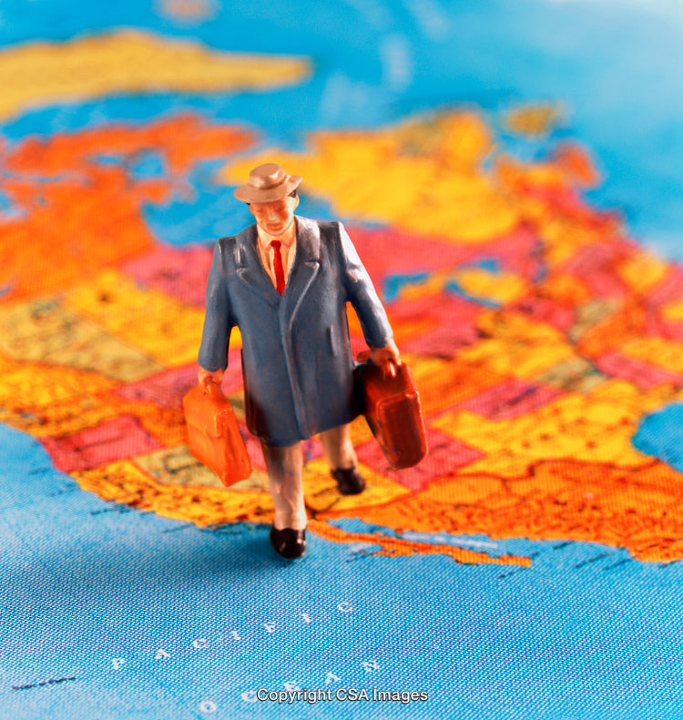 Miniature Traveler Figure Walking Across a Map with Two Suitcases