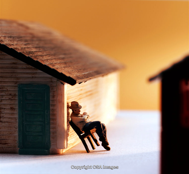 Miniature Figure Relaxing Outside a Rustic House in Warm Lighting