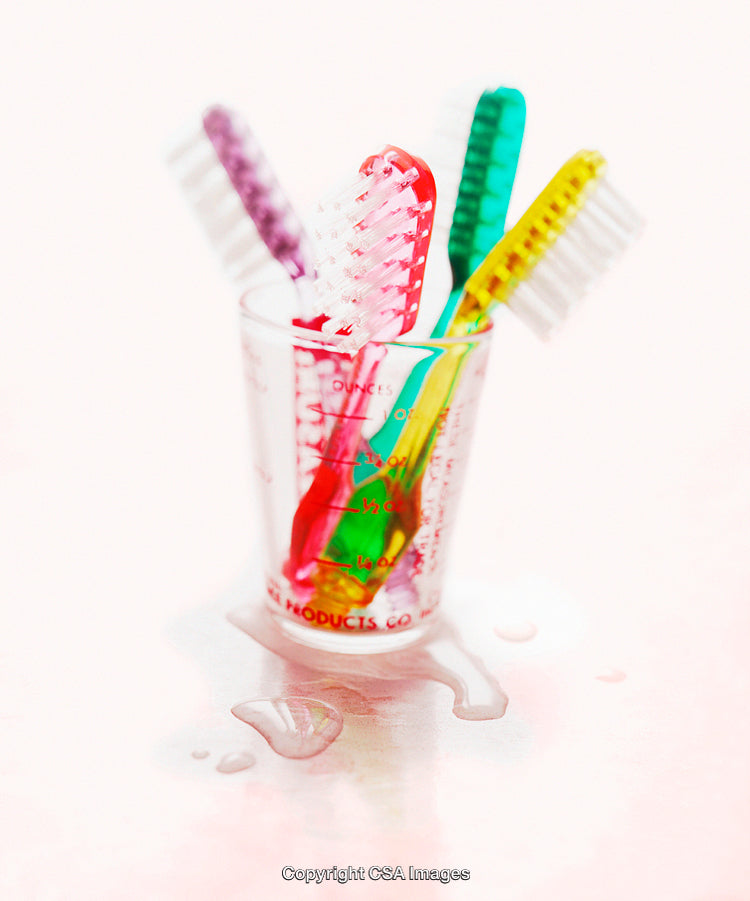 Vibrant Colored Toothbrushes in Transparent Cup with Water Droplets