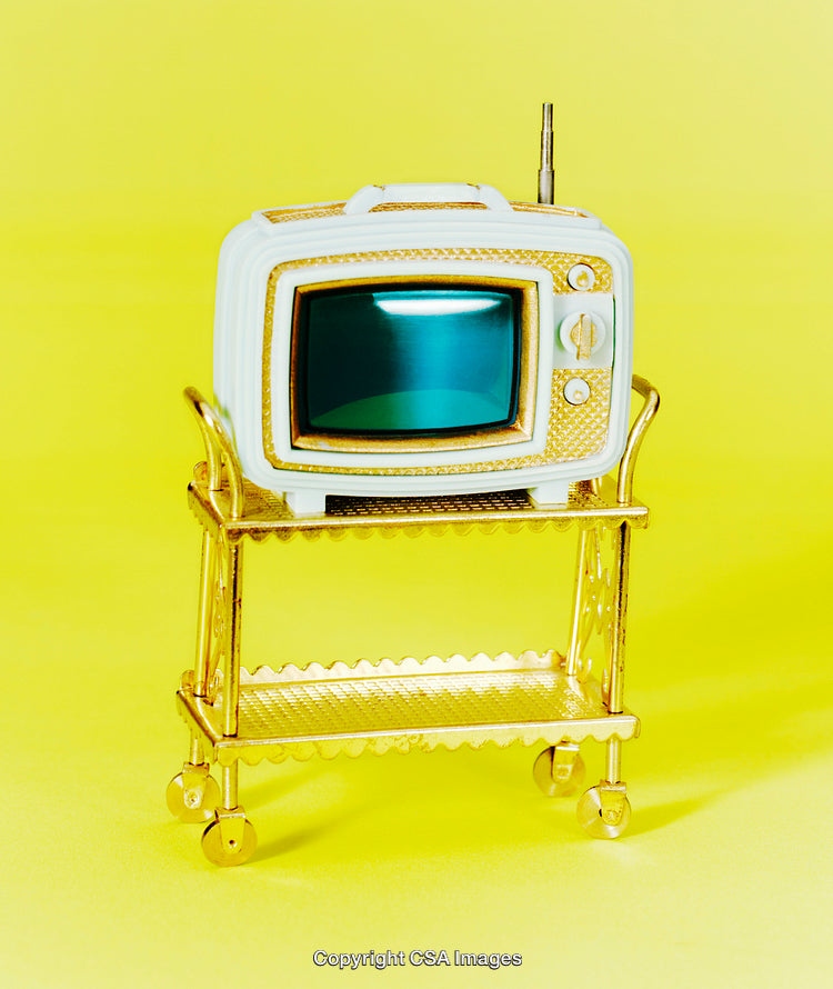 Miniature Toy Television on a Golden Cart Against Yellow Background