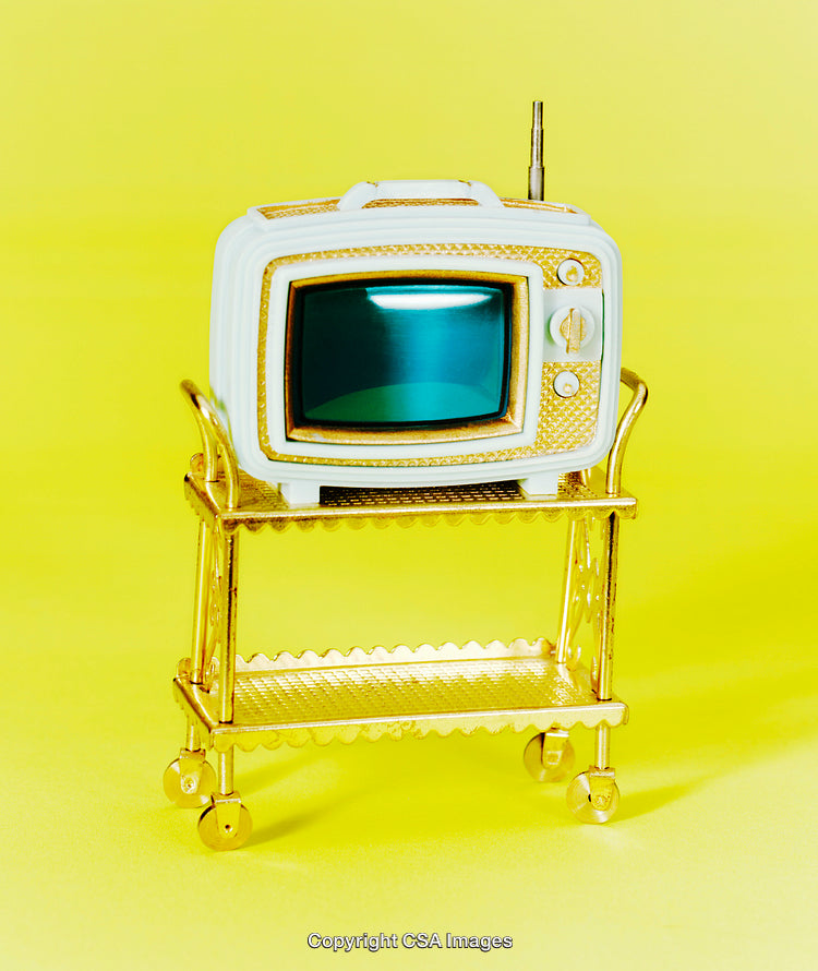 Miniature Toy Television on a Golden Cart Against Yellow Background