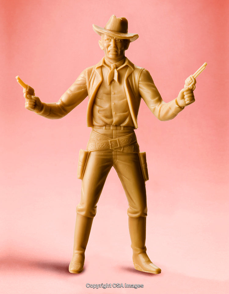 Plastic Cowboy Figure with Revolvers on a Pink Background