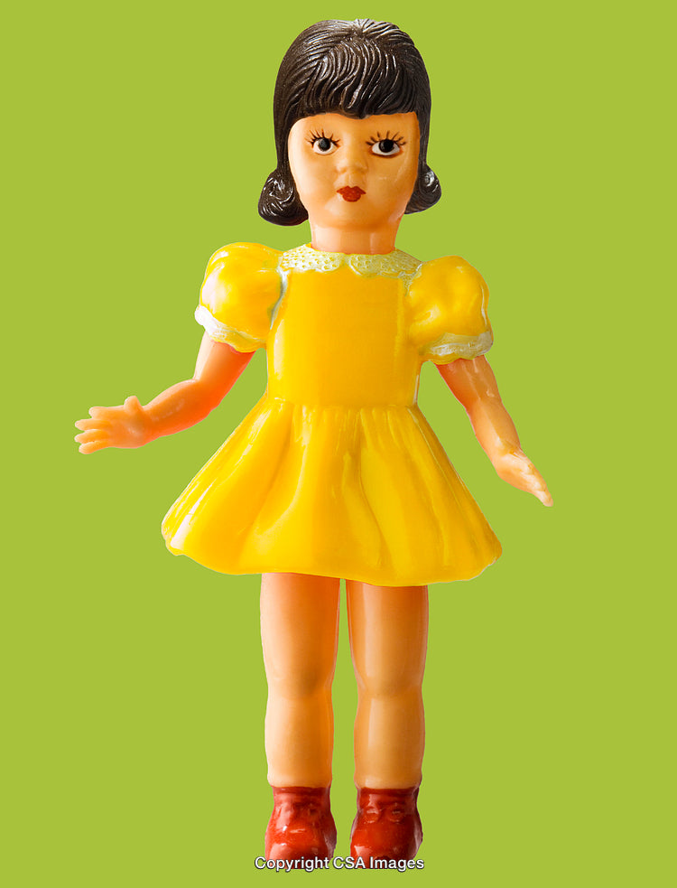 Plastic Toy Doll in Yellow Dress Against Bright Green Background