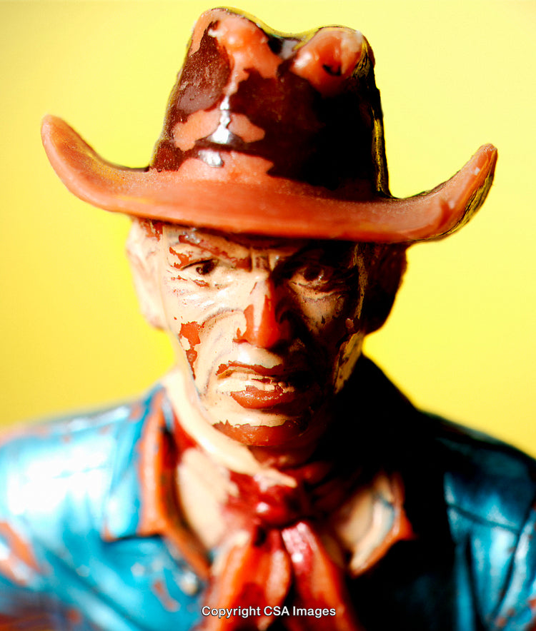 Close-Up of a Painted Plastic Cowboy Figure with Yellow Background