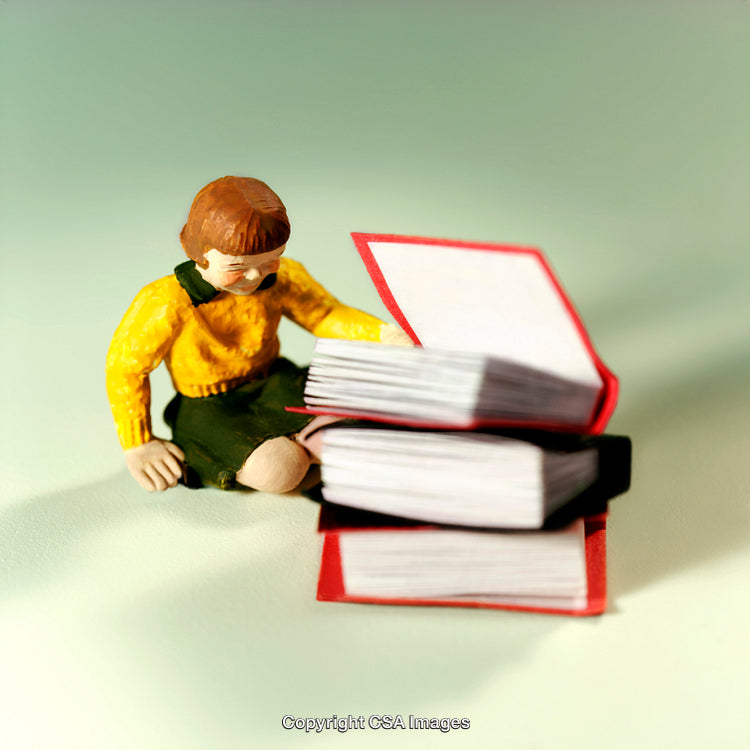 Toy Figurine Reading Beside a Pile of Colorful Books