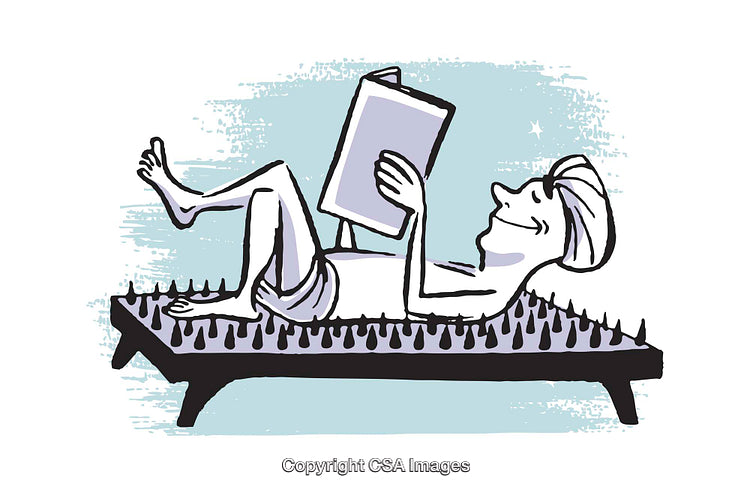 Man Relaxing on a Bed of Nails While Reading a Book