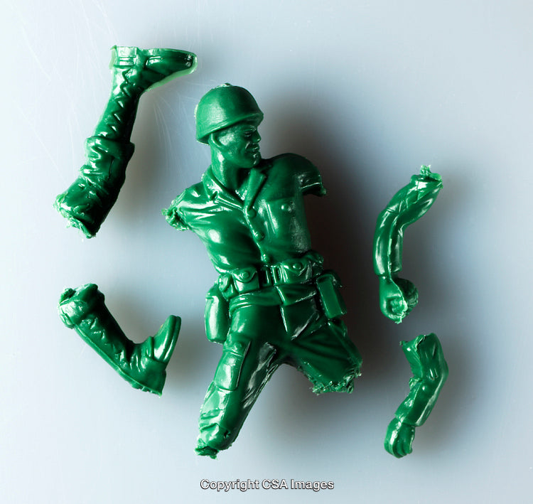 Broken Green Plastic Toy Soldier Pieces on a Gray Surface