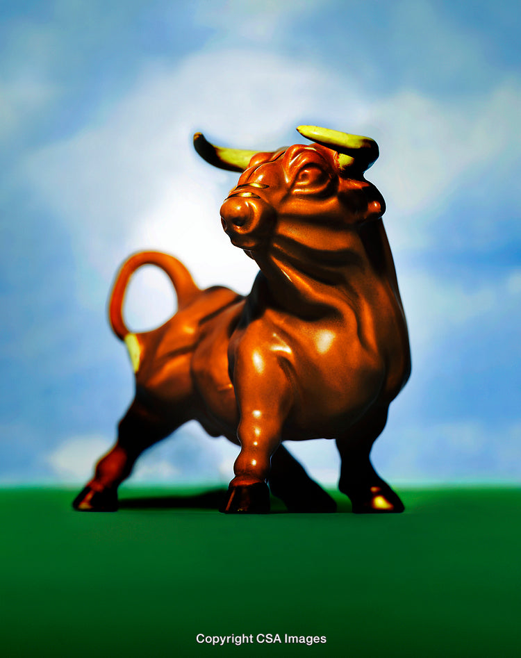 Golden Bull Figurine Against Blue Sky and Green Background
