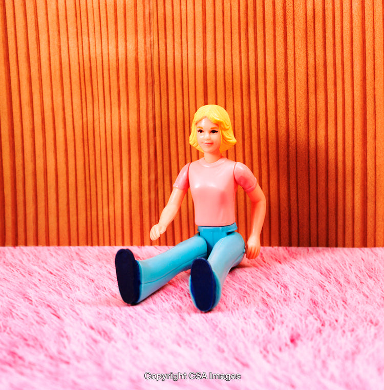 Plastic Toy Figurine Sitting on a Vibrant Pink and Wooden Surface