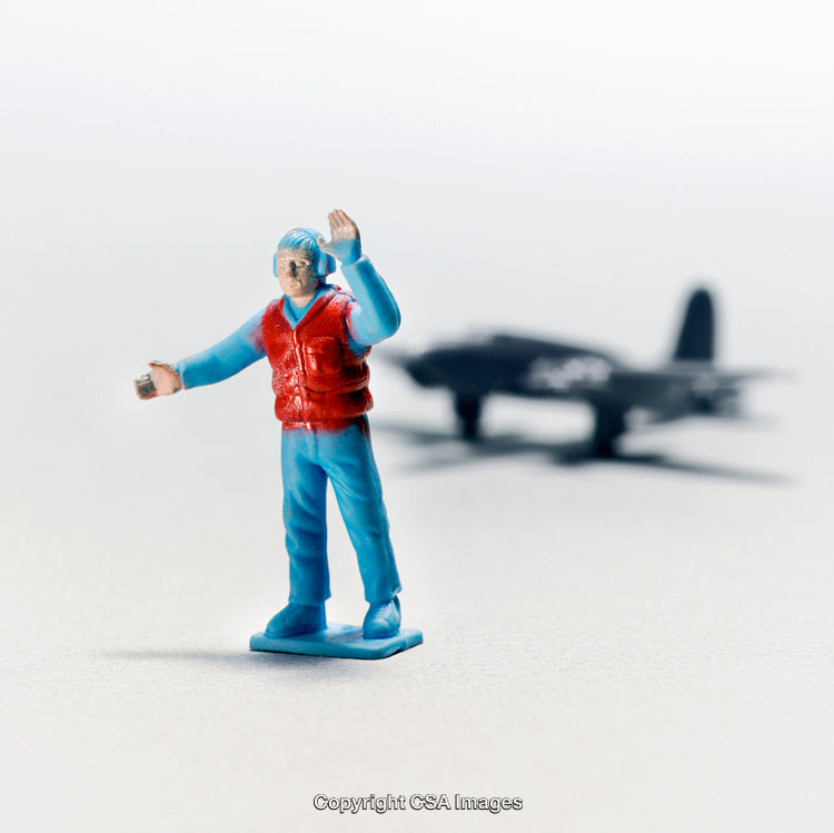 Miniature Figure of Person with Toy Plane in Background