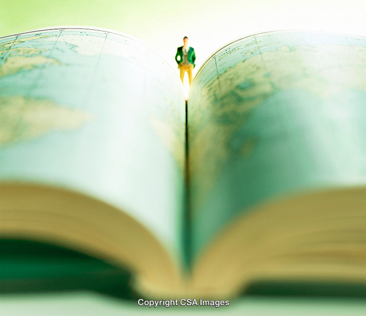 Miniature Figure Standing on Open Atlas Book with Blurred Background