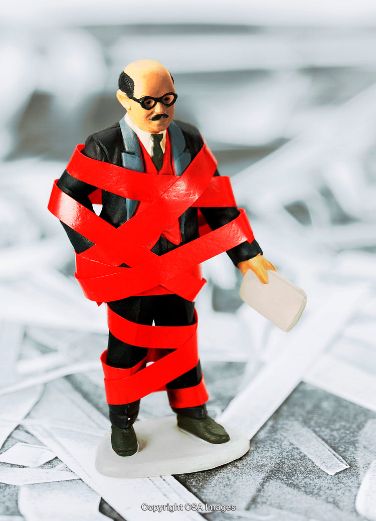 Miniature Businessman Restrained by Red Tape on Abstract Background