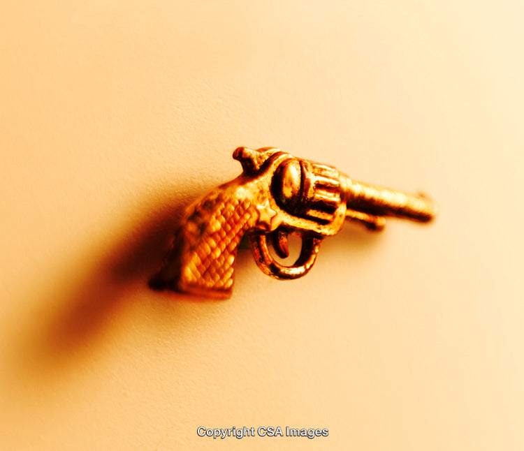 Golden Toy Revolver Against a Soft Neutral Background
