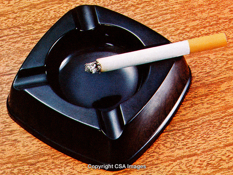Lit Cigarette in a Black Ashtray on a Wooden Table Surface