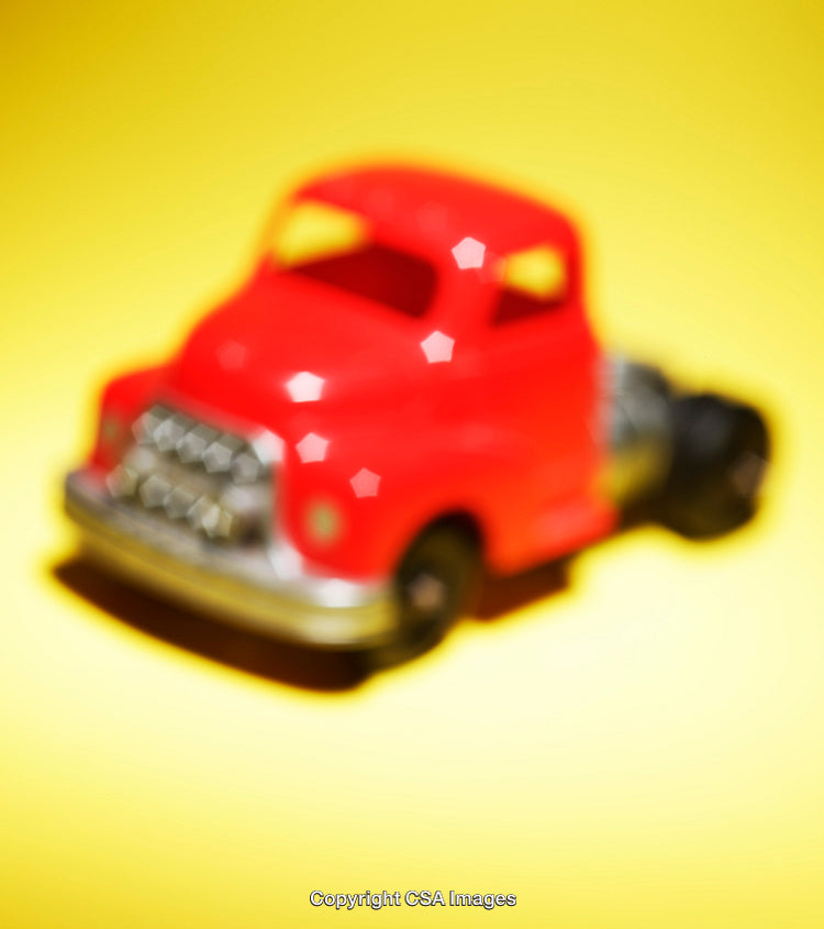 Blurred View of Red Toy Truck on Vibrant Yellow Background